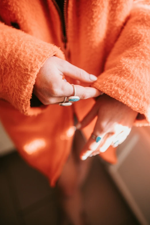 someone in an orange robe with white manicures and a matching ring