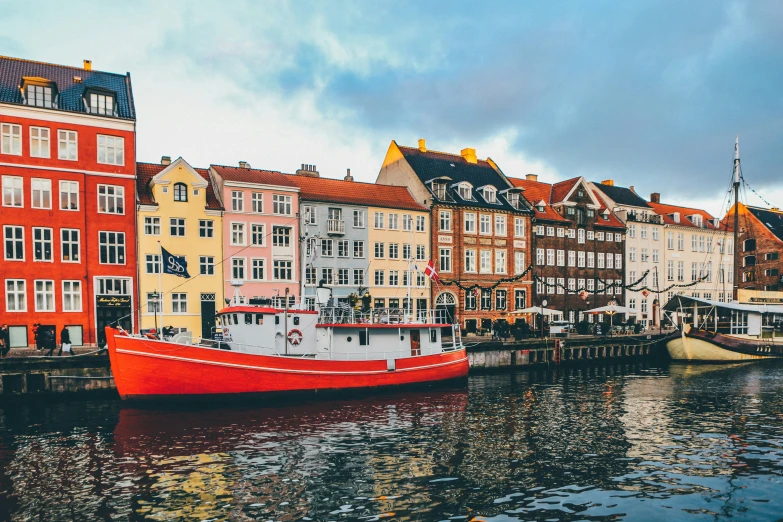 a red and white boat is docked on the water near a group of buildings