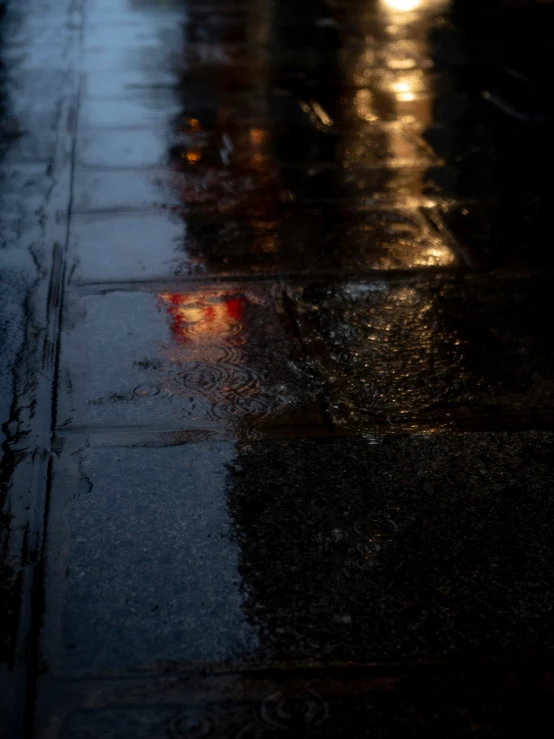 the light of streetlights shine on a wet sidewalk