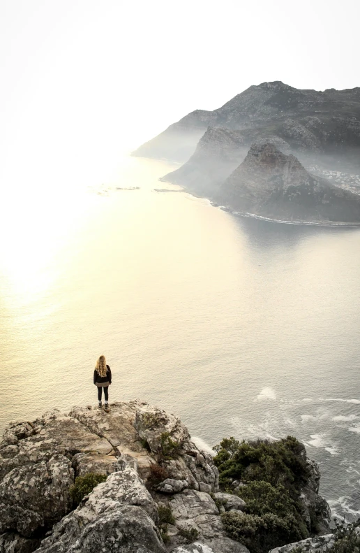 a man standing on top of a large rock near the ocean