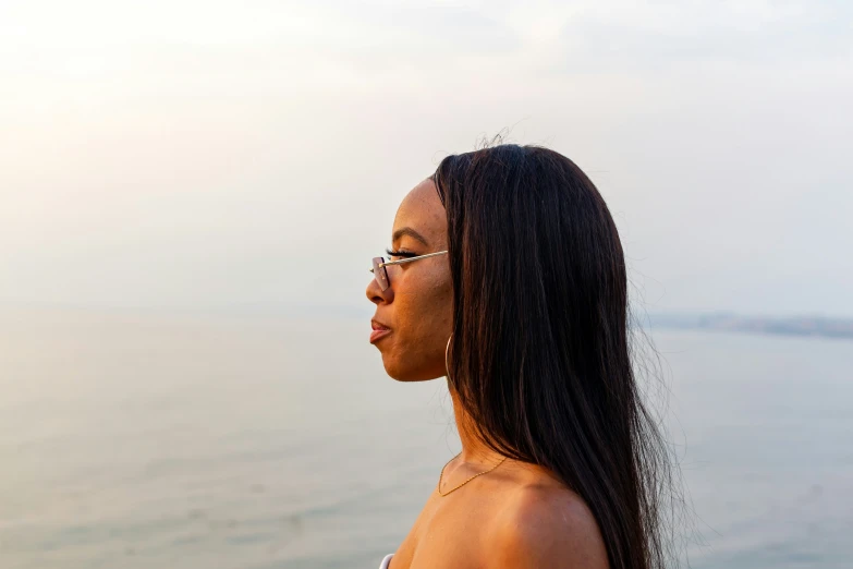 a woman with glasses standing in front of water