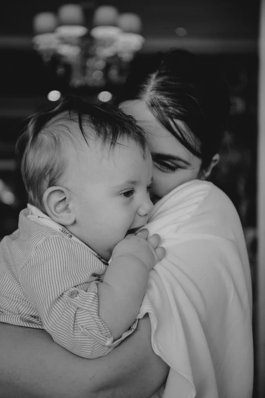 the mother holds her toddler boy close to his neck