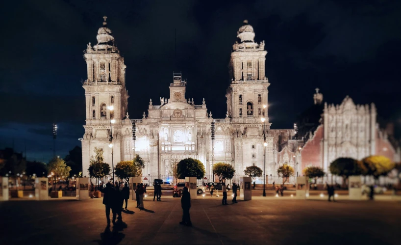 several people are walking toward the illuminated cathedral