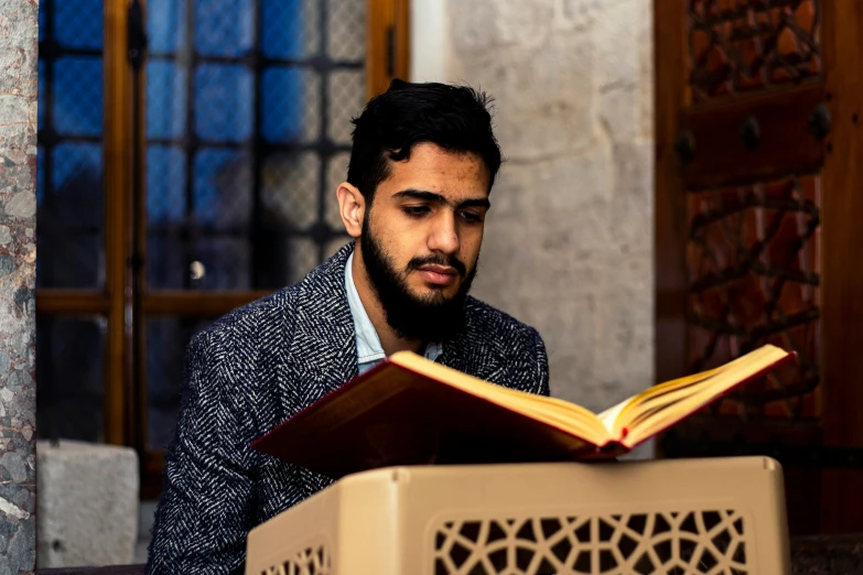 a man wearing a suit and sitting reading a book