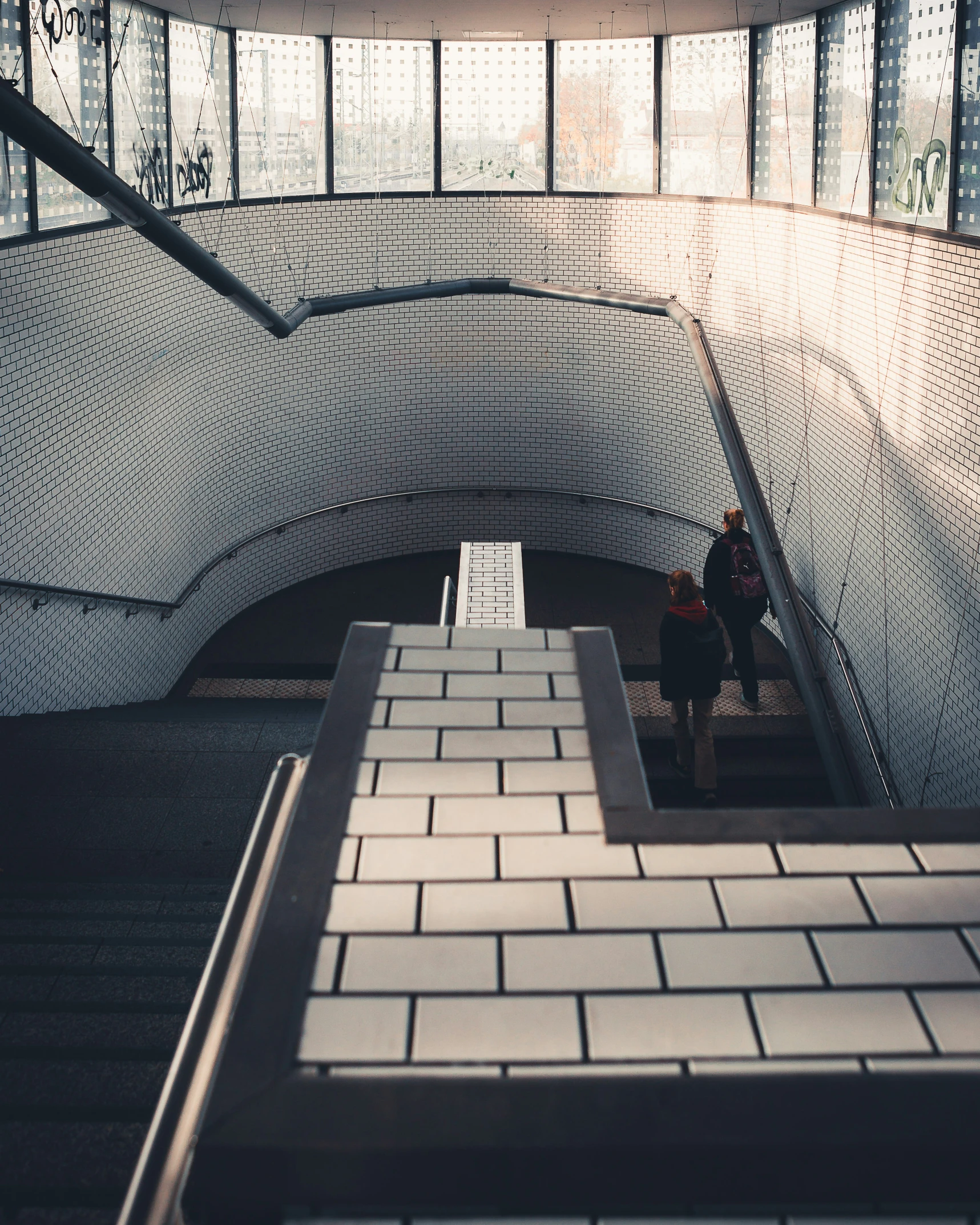 a man is walking up the stairs near some glass windows