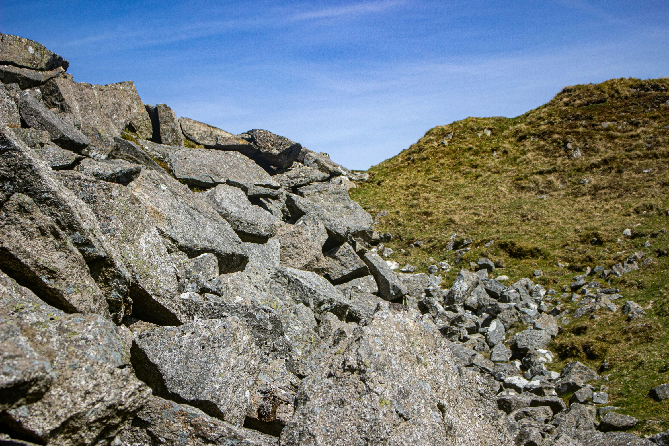 a person walking down a rocky slope next to a hill