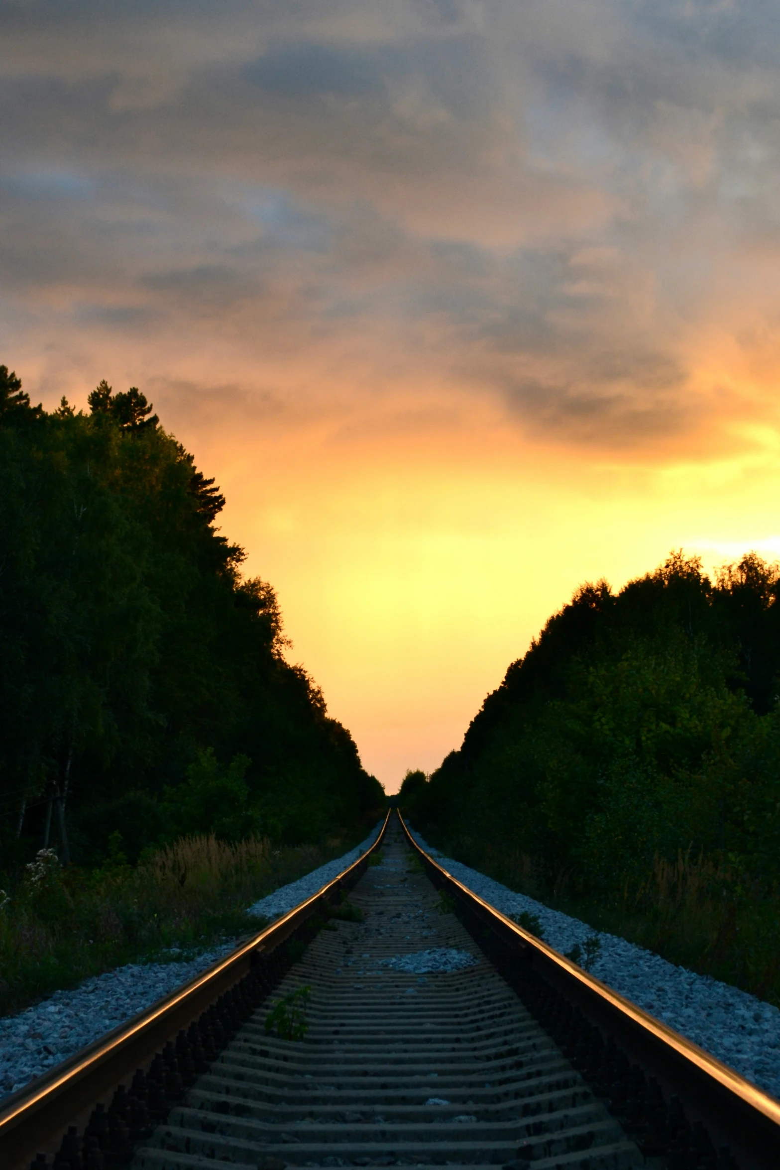 the view from an empty railroad track at sunset