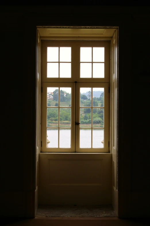 a window with open shades overlooking a body of water