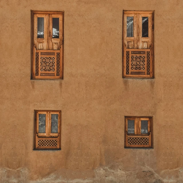 four windows are next to each other in front of an adobe building