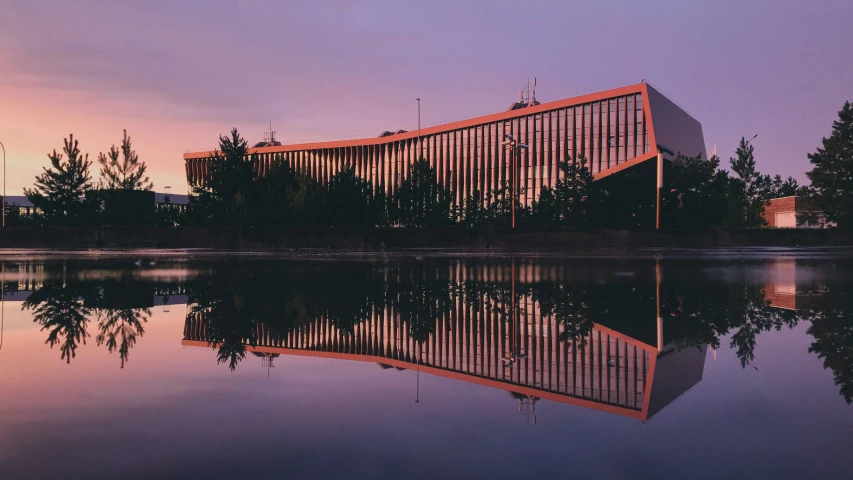 a building sits next to a body of water with trees surrounding it