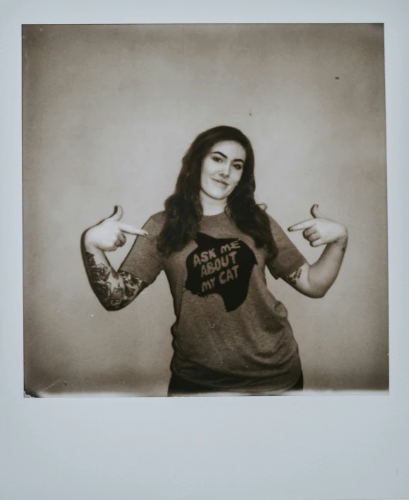 a woman wearing a heart shirt, holding out two fingers