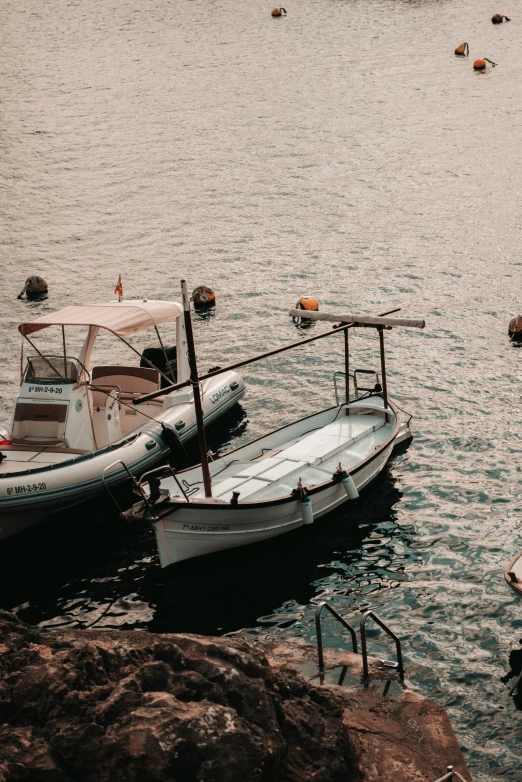 two white boats are tied to the rocks in the ocean