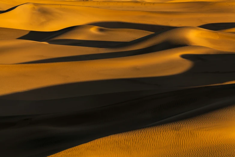 a sandy desert area with long shadows on the sand