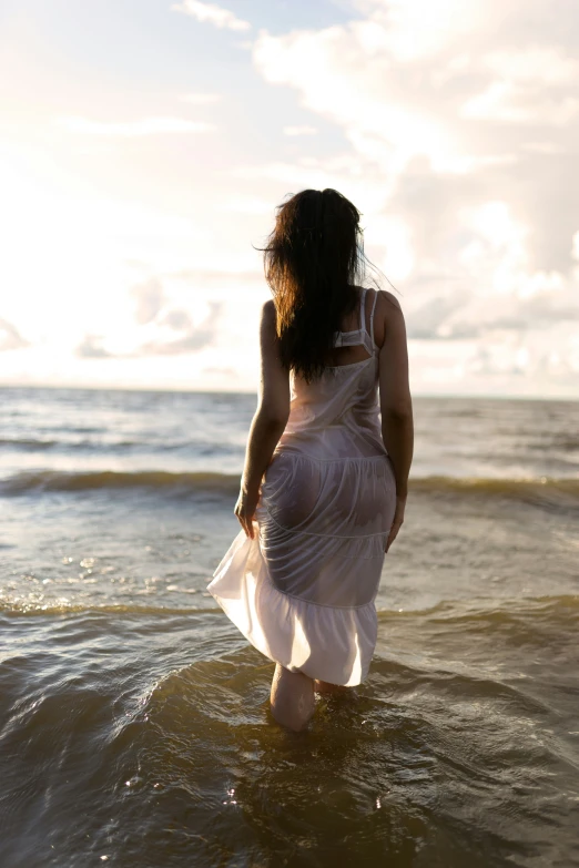 a woman wearing white is wading in the ocean