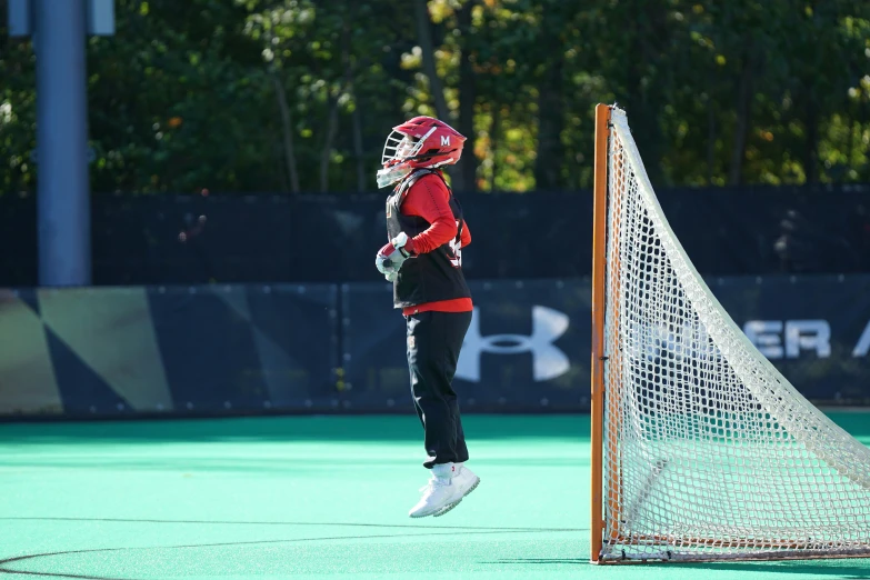 a young lady in a red shirt and black pants is practicing lacrosse