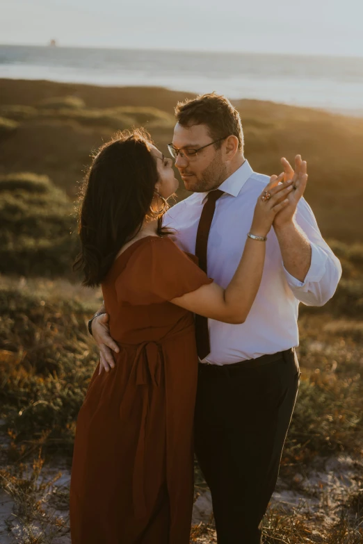 a young man and woman dancing on a beach