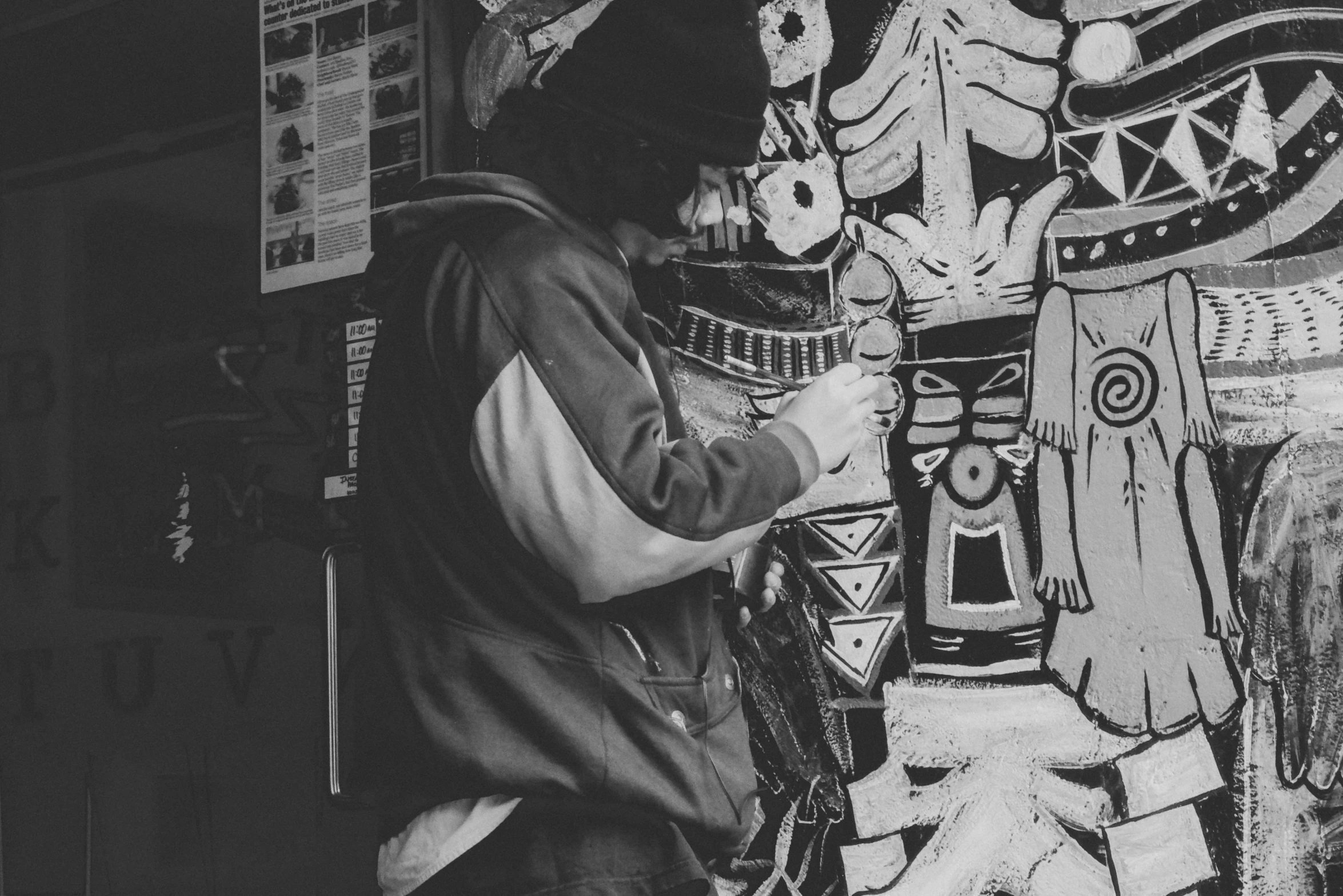 a black and white image of a person painting a mural