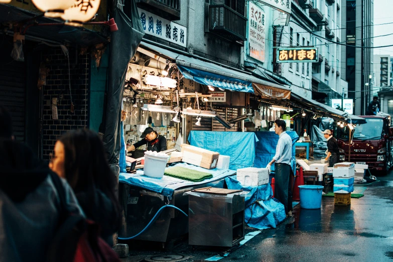 people are walking through an outdoor market near buildings