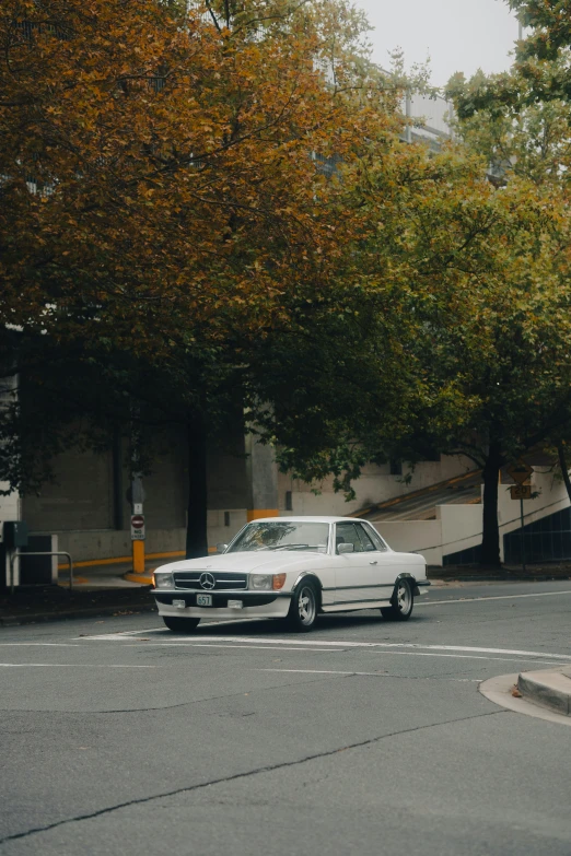 this is a white vintage car on a paved street