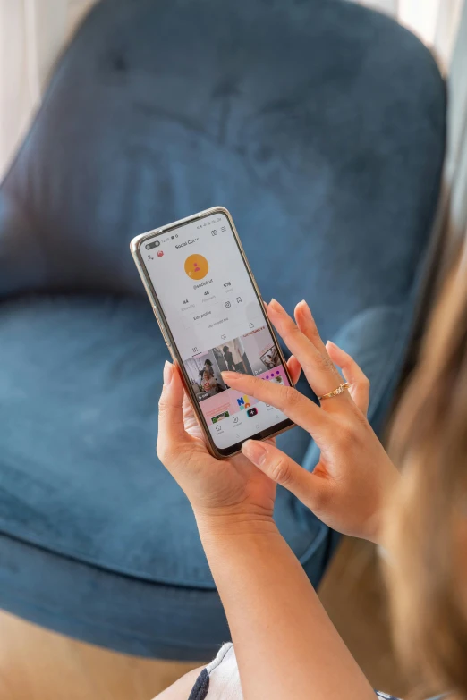 woman with glasses holding and looking at her cell phone