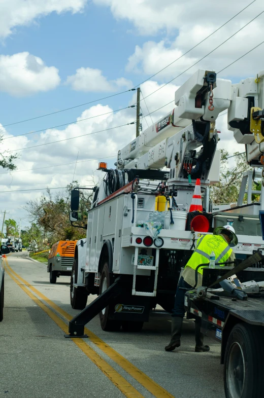 construction workers work on a telephone pole on a street