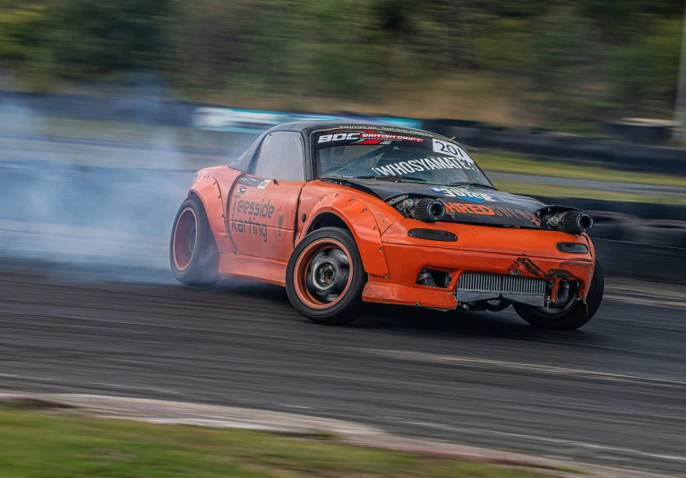 an orange sports car with burn em up from the engine on a track