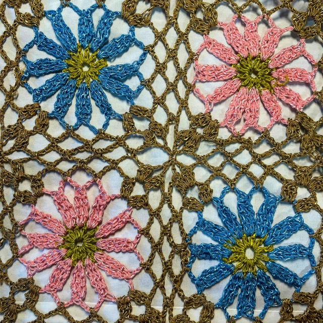 four crocheted flowers in blue, pink and green