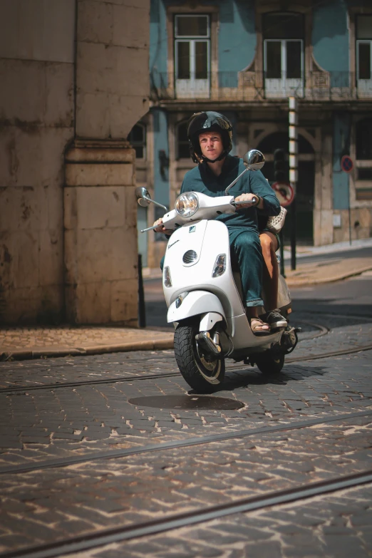 a man is riding a white scooter down a street