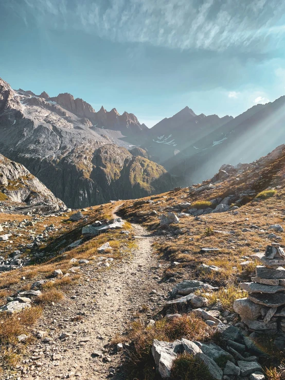 a rocky trail in the mountains with sun shining on it