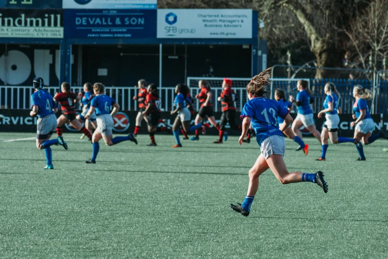 some people playing rugby with another team of people watching