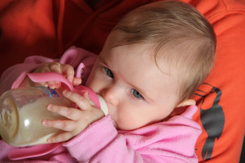 the baby girl drinks from a glass cup