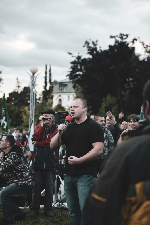 a man holding a microphone with two others looking on