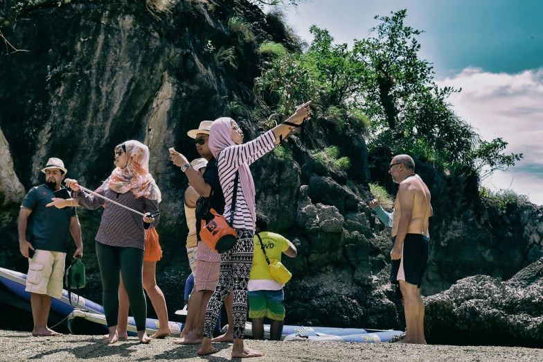 a group of people standing in the sand near water