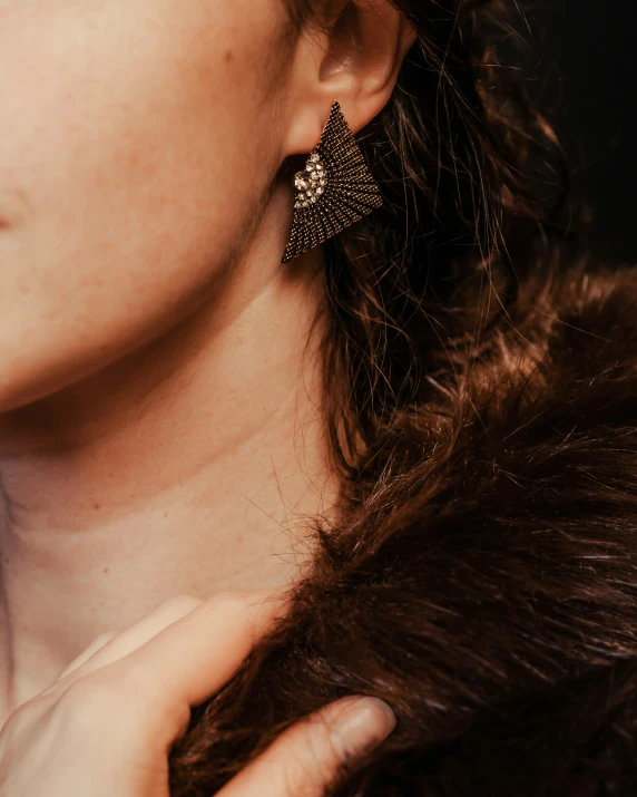 a woman wearing big shiny gold earrings on her ear