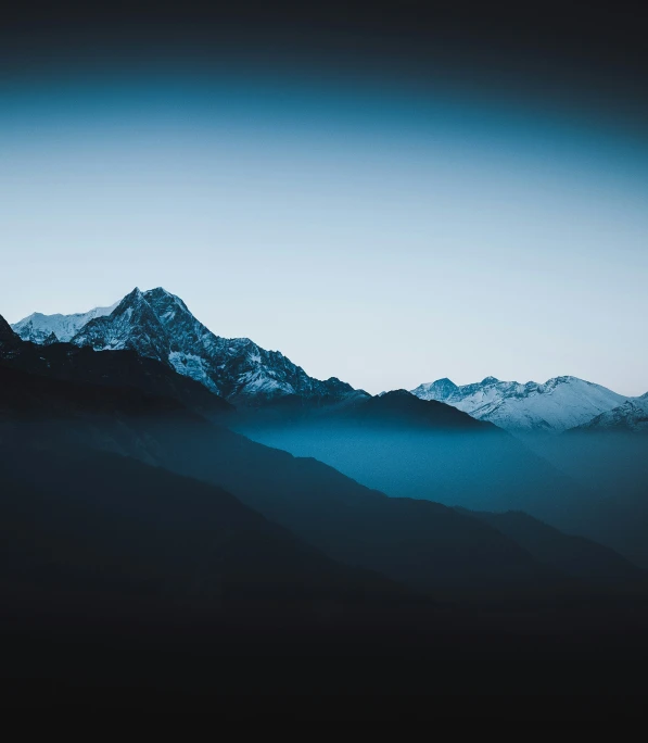 the silhouette of a mountain range with snow on it