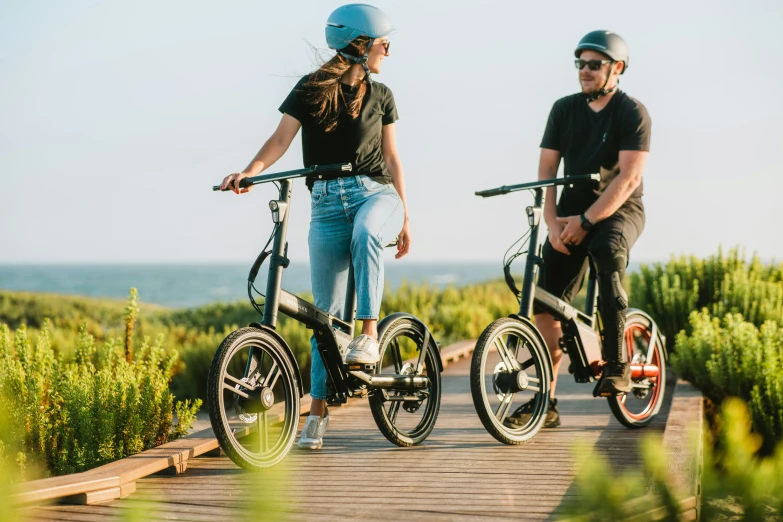 two people are standing near the beach on bikes