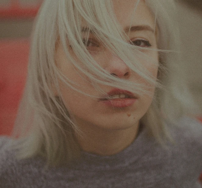 a woman has white hair and is looking off into the distance