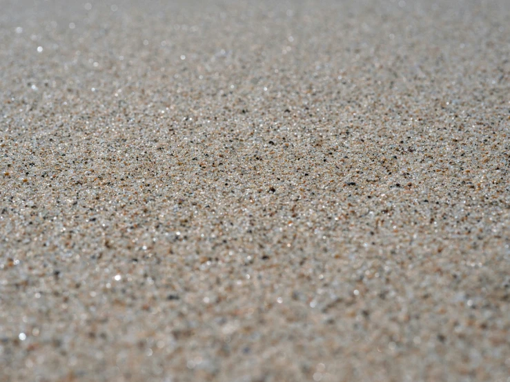 a sand covered area with tiny dots, water drops and white sand