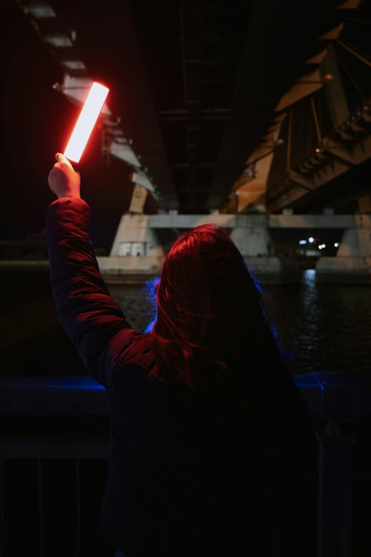 woman holding a light on top of a bridge at night