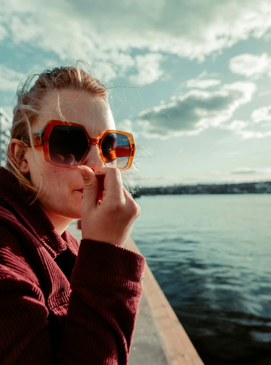 a young lady sitting at the side of a pier on a sunny day