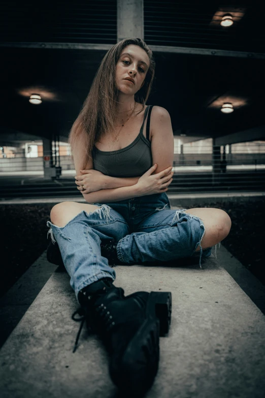 a beautiful young woman sitting on the ground wearing boots