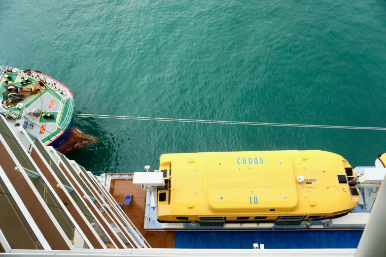 a yellow boat in the ocean next to another white boat