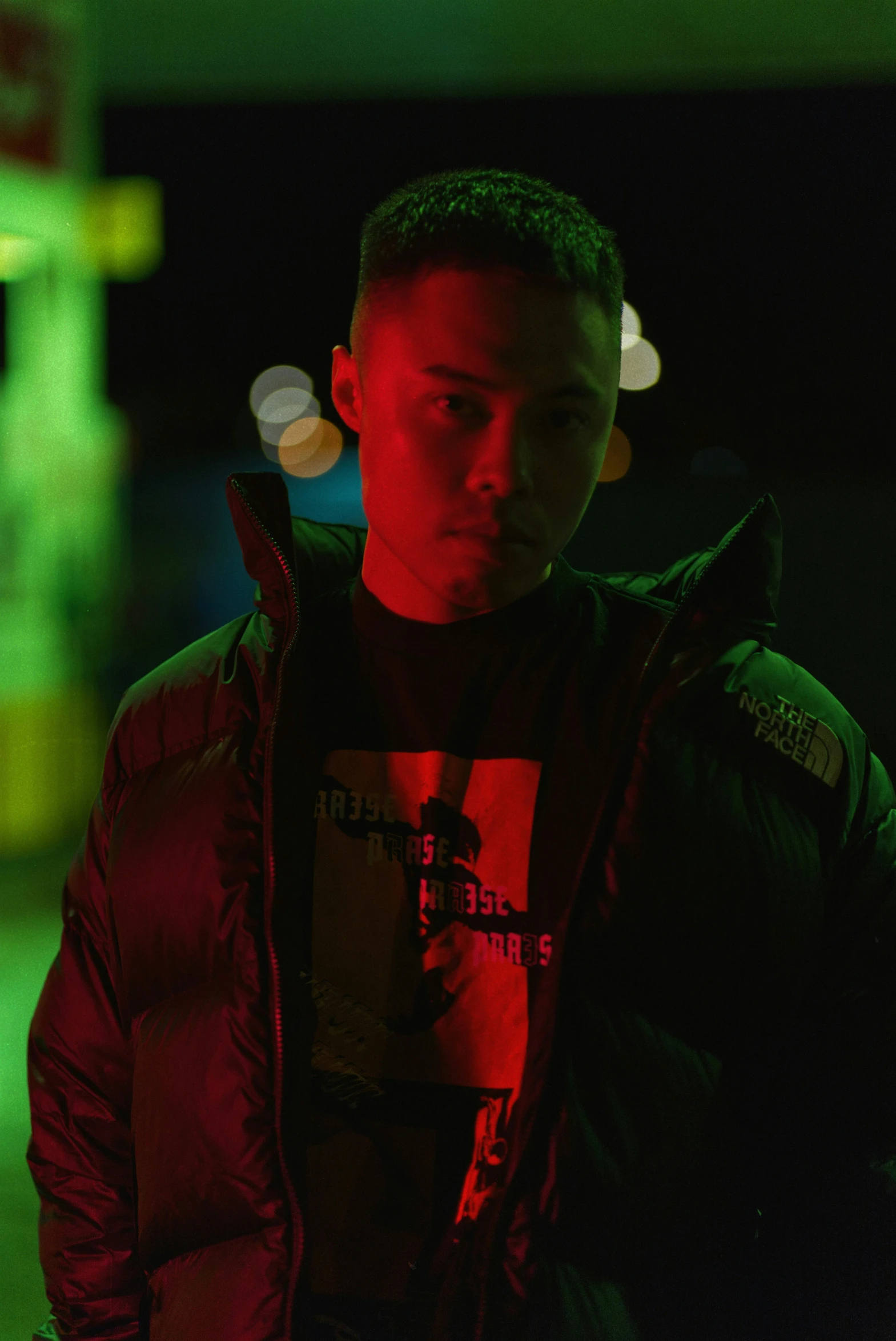 young man standing in the dark in an area with lights in background