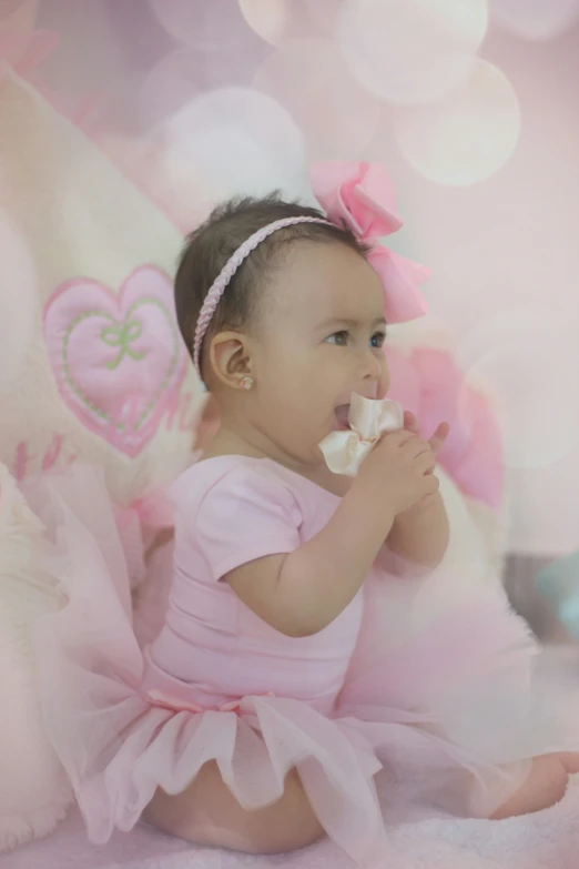 a baby girl in pink and pink dress sitting on a pink blanket