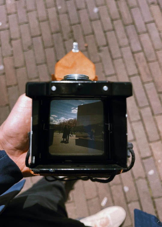 a hand holds up a camera that is open and shows food in the background