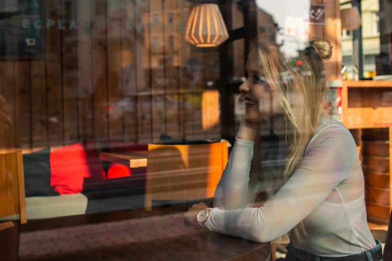 a beautiful young lady talking on a phone outside a restaurant