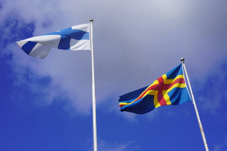 two flags are flying in the wind on top of a building