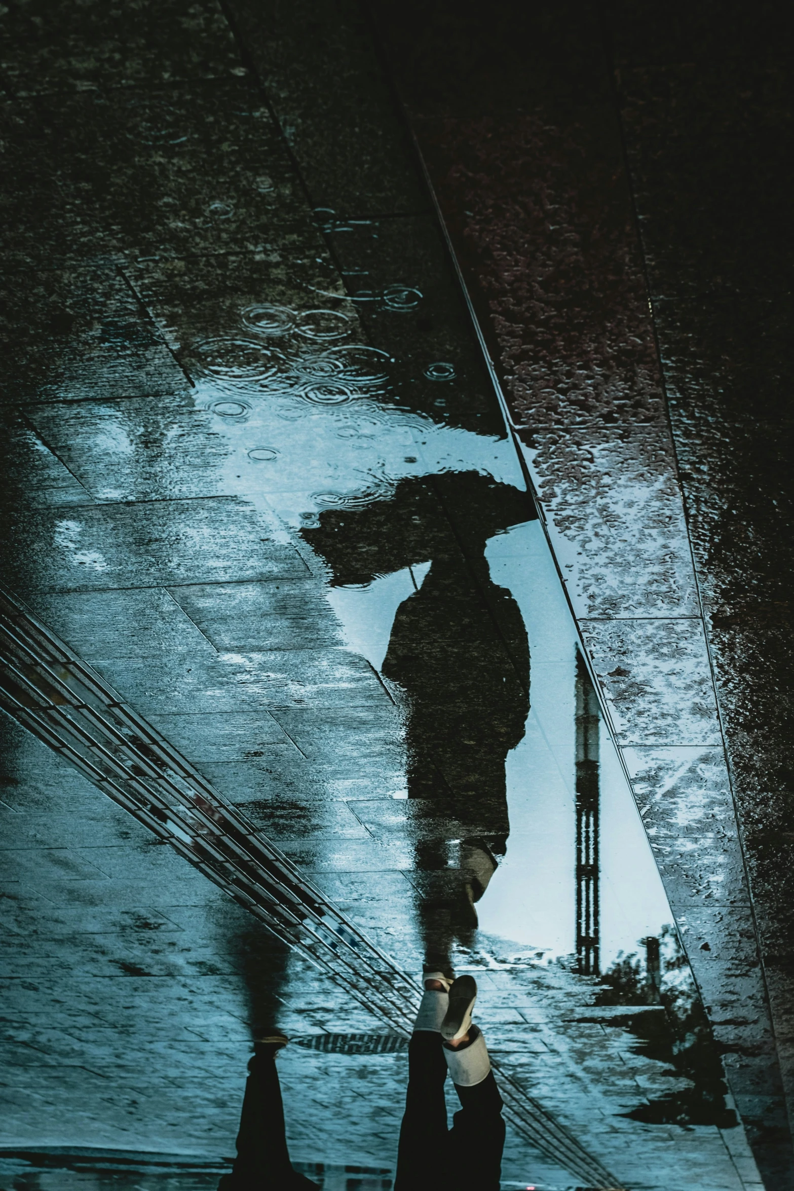 reflection of two people holding umbrellas walking in the rain