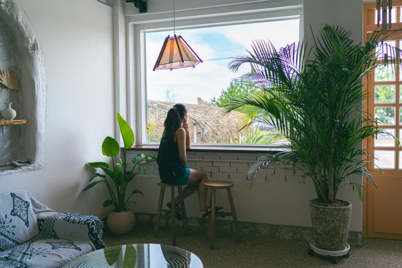 a woman sits at a window in a room