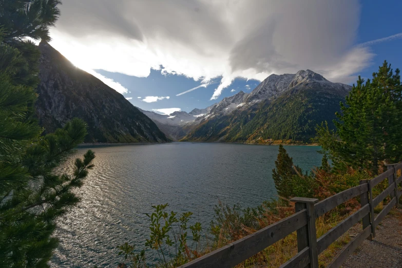 the lake is surrounded by high mountains on a partly cloudy day